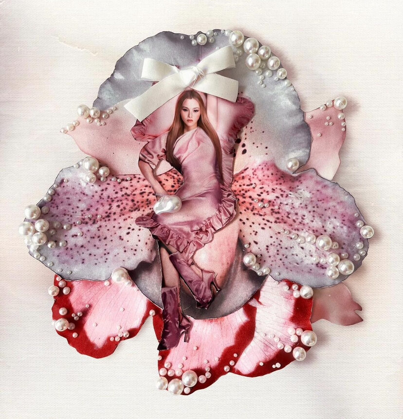 3D art piece of a woman dressed in pink sitting on a lavender, pink, and red oversized flower with pearls and a singular white bow on the petals.