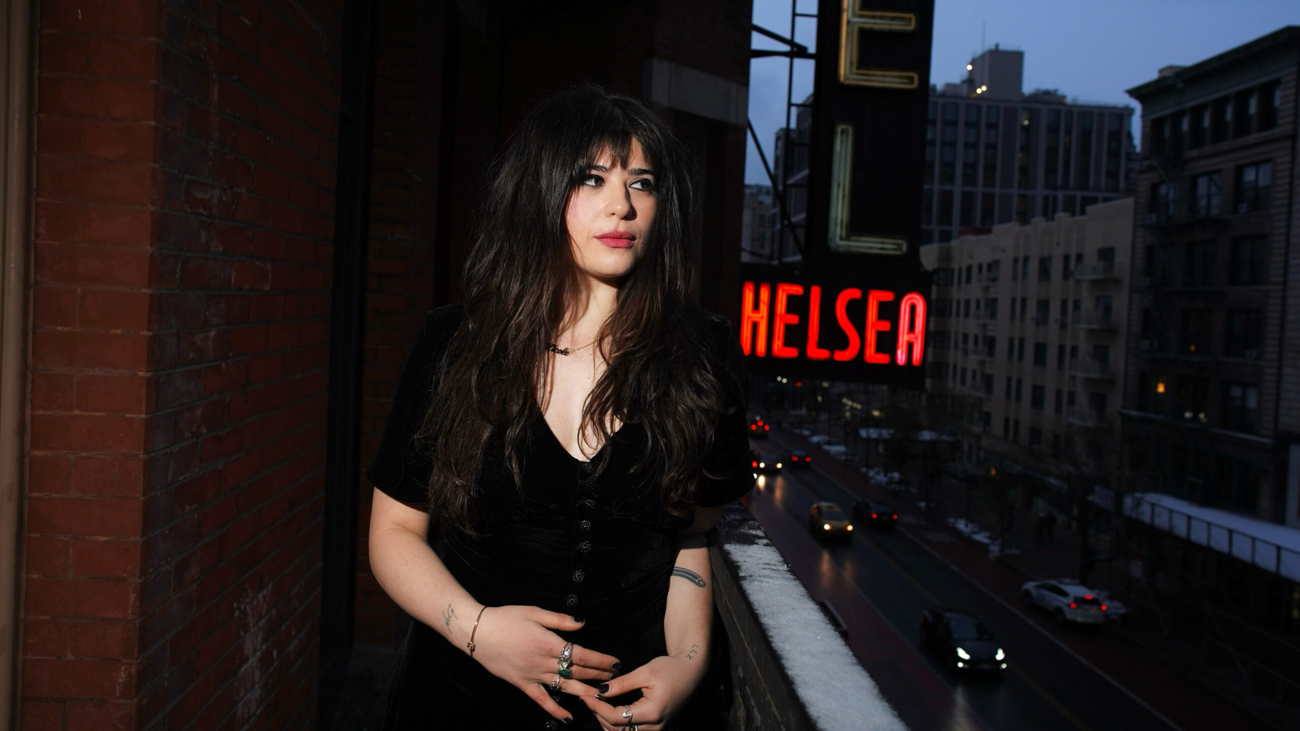 Nicole Galinson poses on a balcony in front of a lit-up red Chelsea sign.