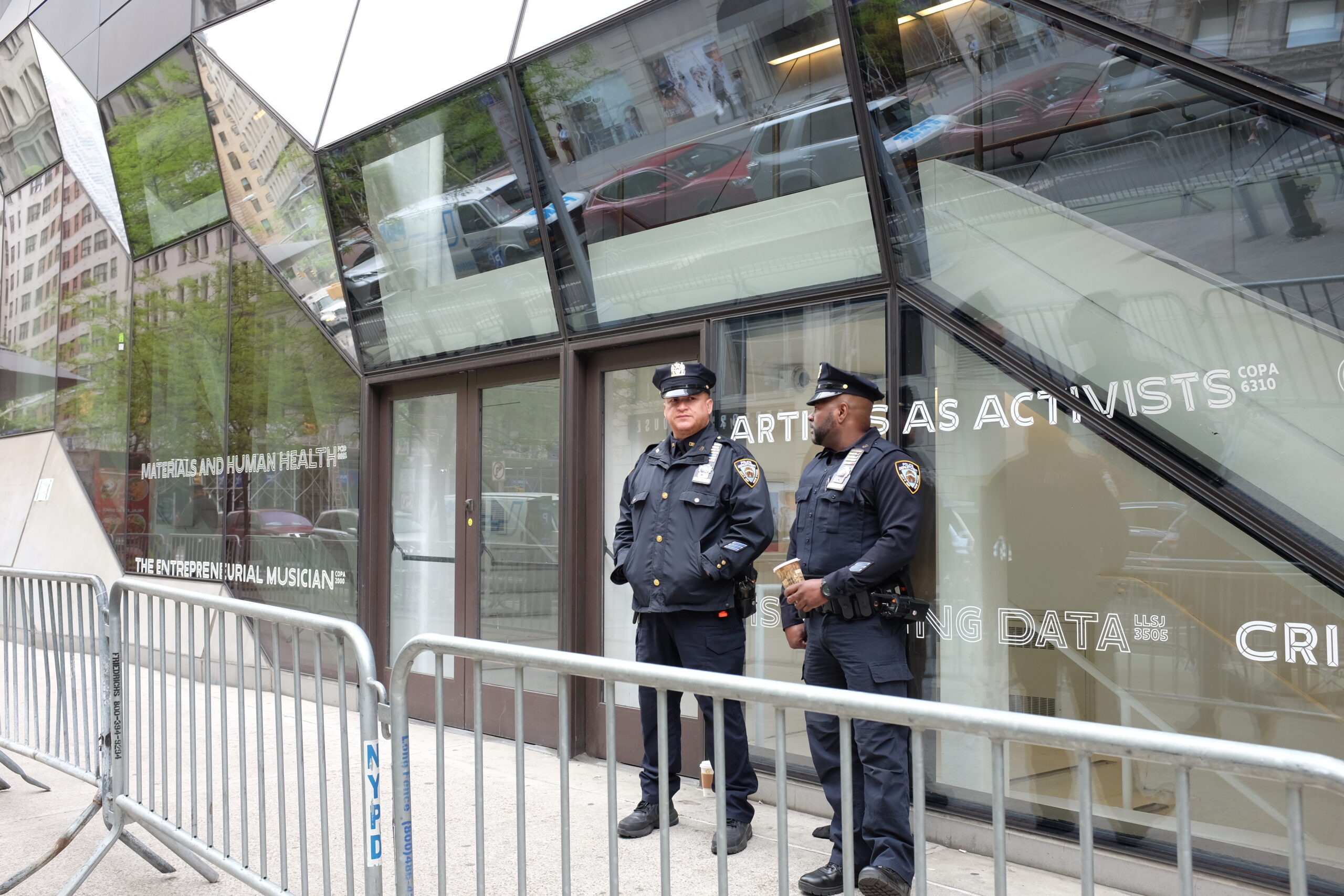 NYPD officers stand outside of University Center behind a barricade