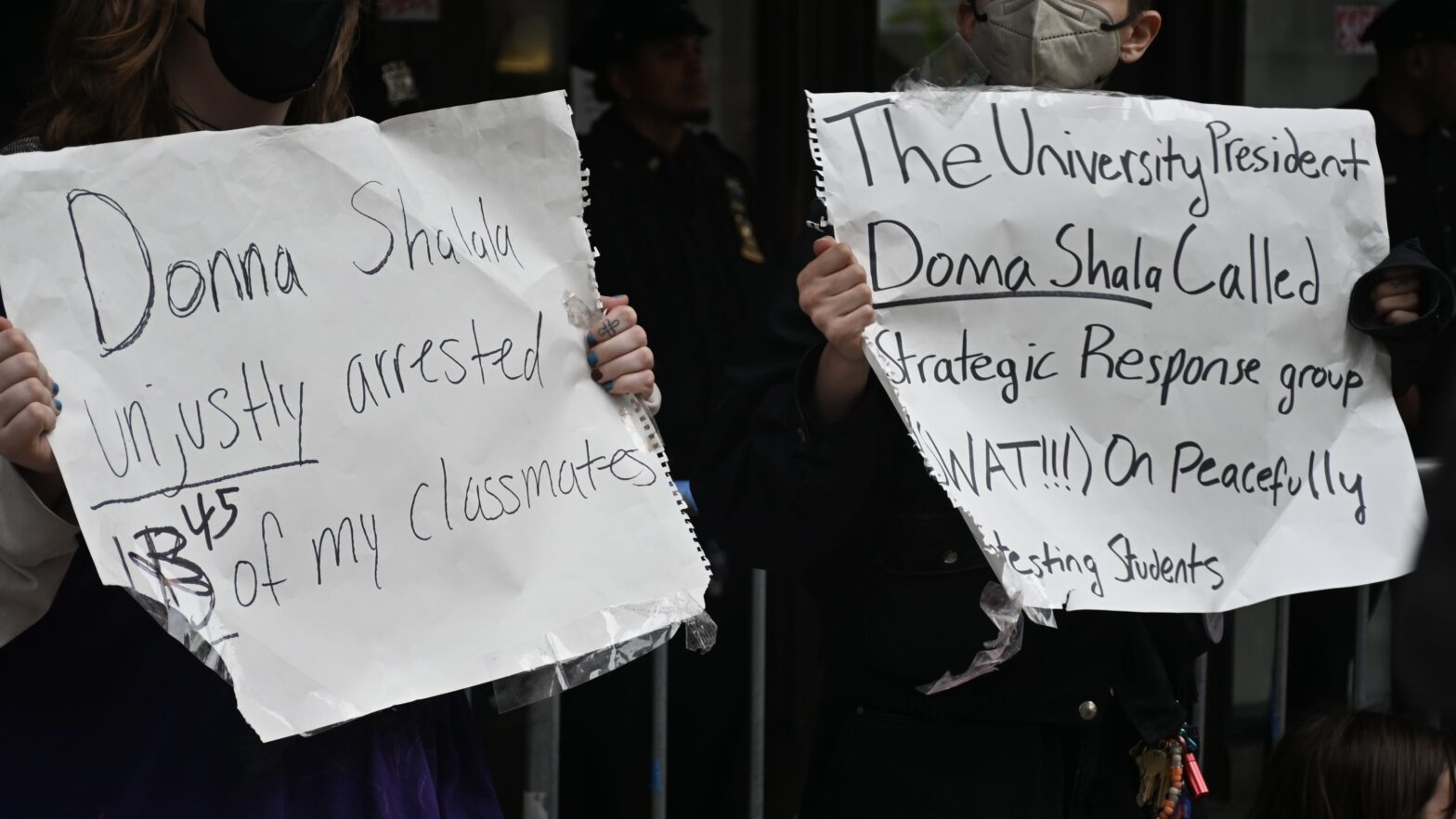 two signs on white paper held up at a University Center rally calling out Donna Shalala for arresting TNS students