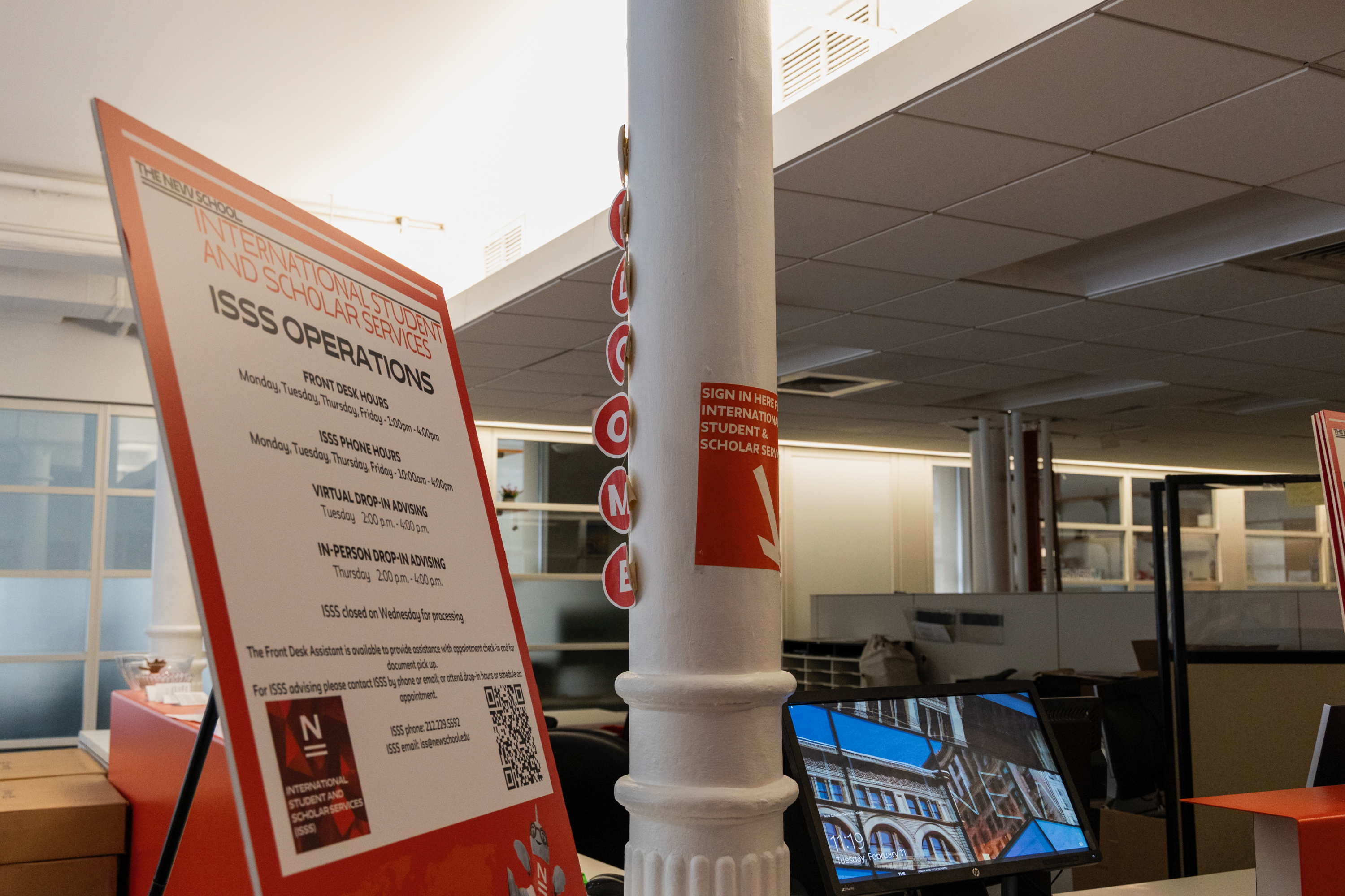 International Student and Scholar Services desk at the 72 Fifth ave building. A sign is on the right showing the hours the office is open
