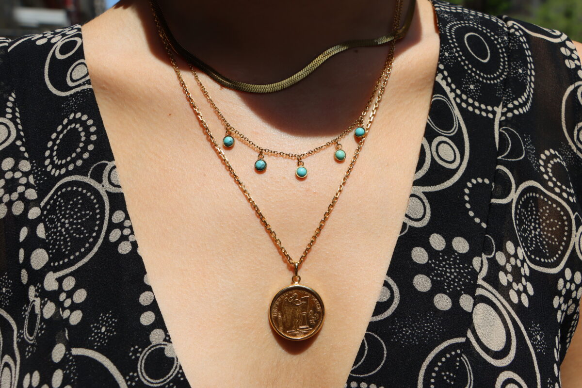 Close-up of a student’s three necklaces and black geometric floral top.