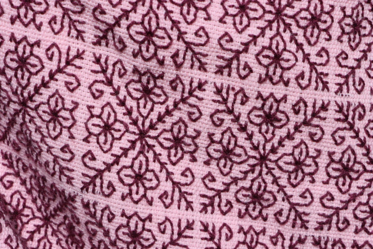 Close-up of student’s pink poncho with flower and vine detailing.