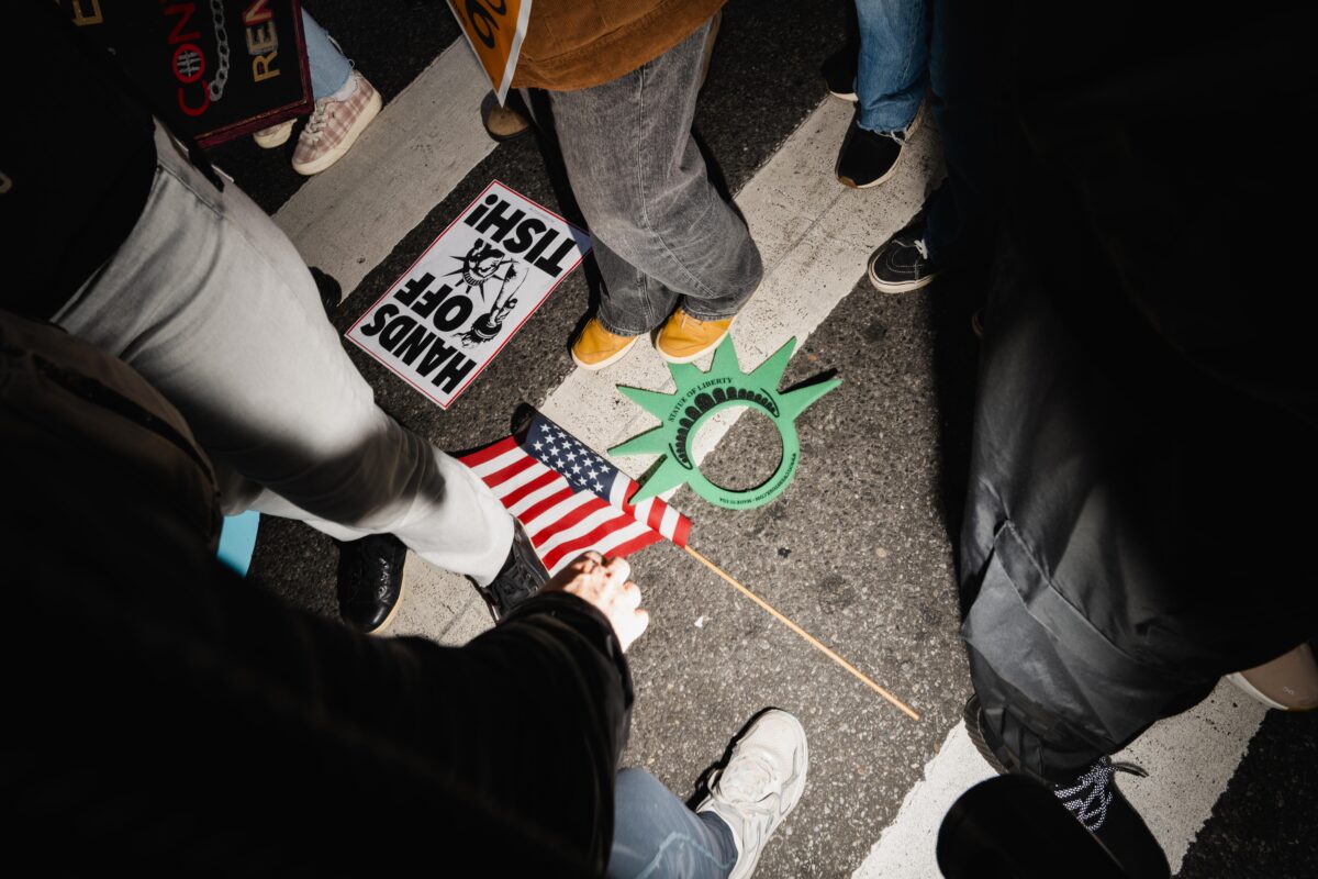 Signs and an American flag lay on the street between the legs of people