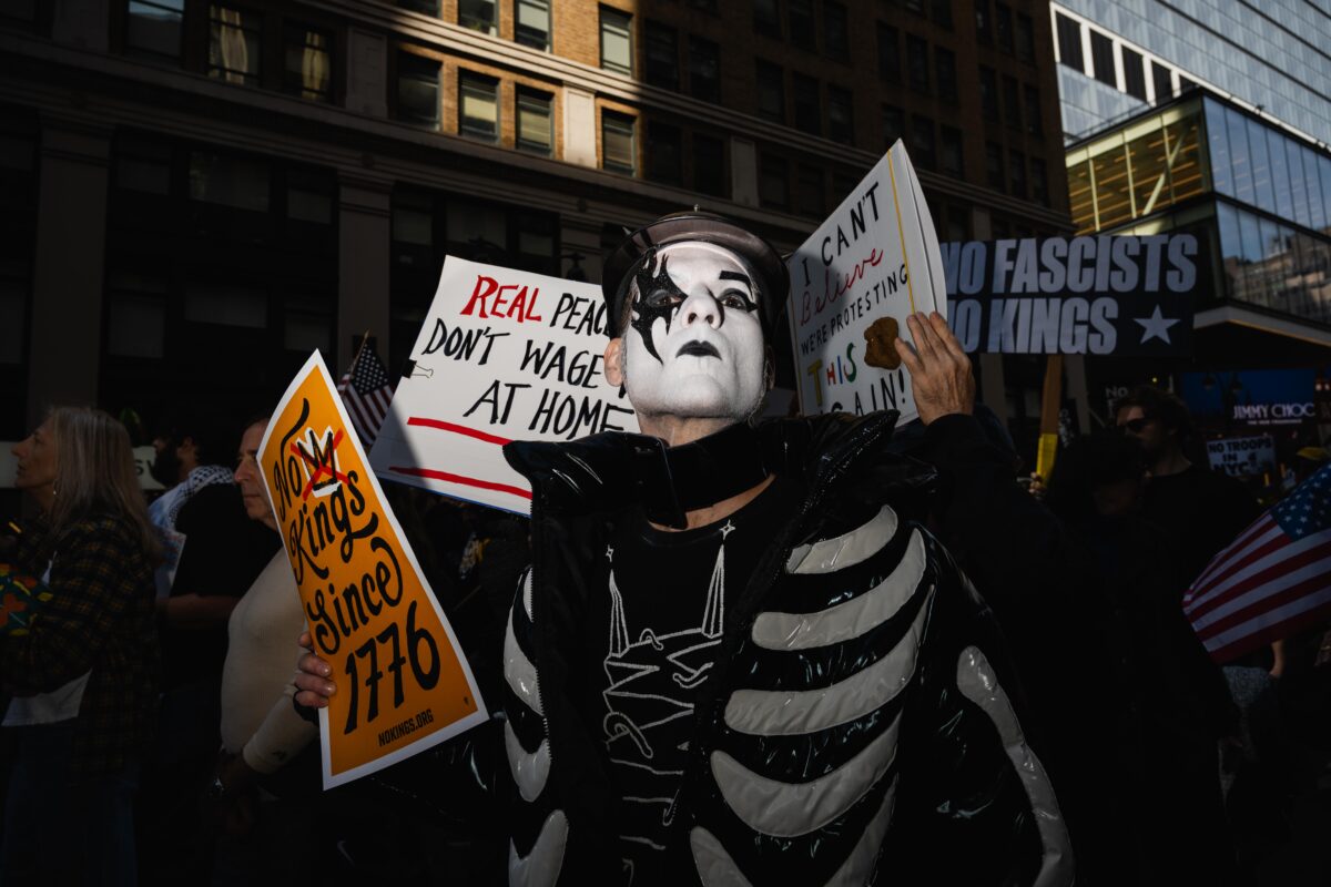 Person in black and white outfit protesting and holding signs 
