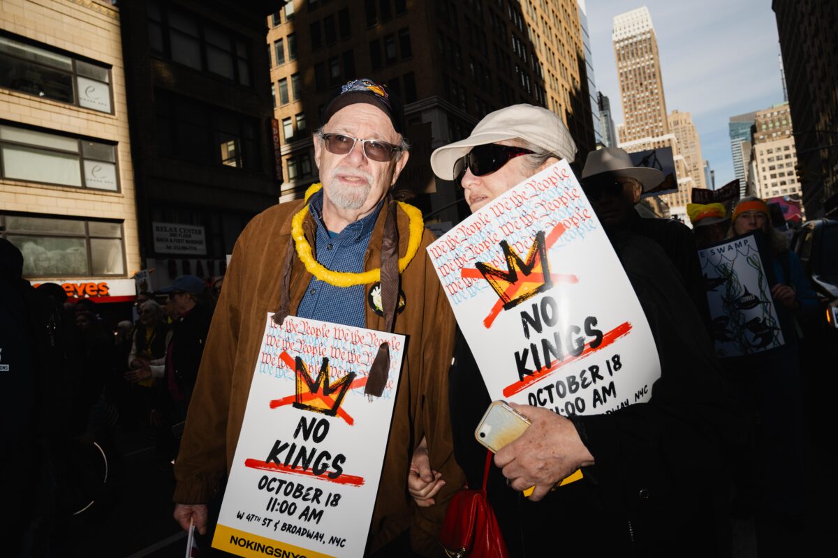Older couple holding protest signs together.