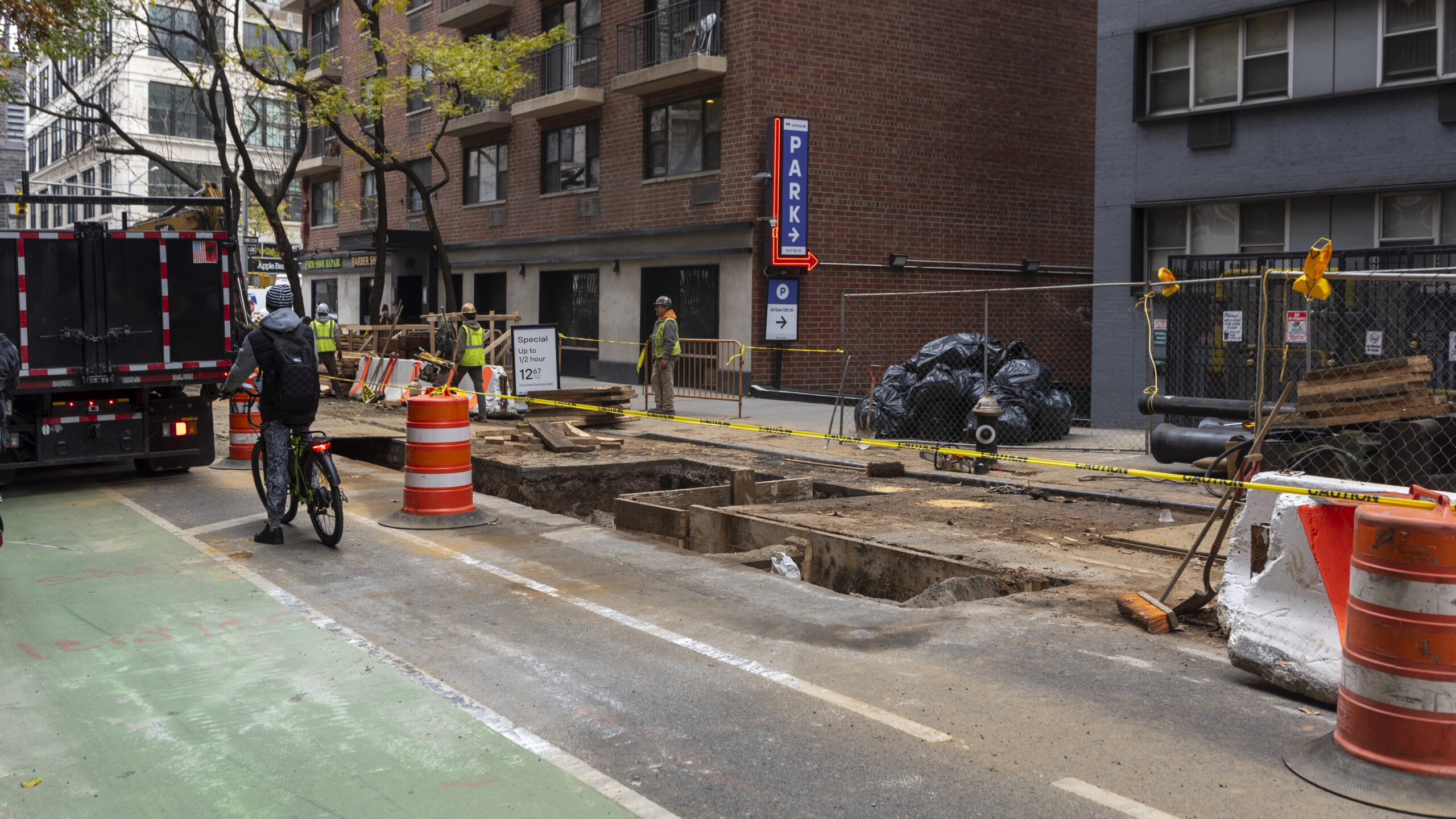 Construction workers dig on one side of the road, blocking traffic from passing.