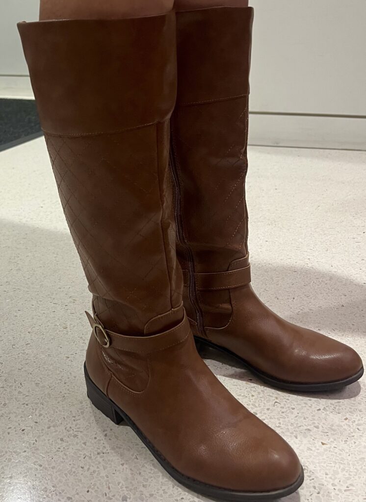knee-high brown leather boots with a buckle on the ankle. 
