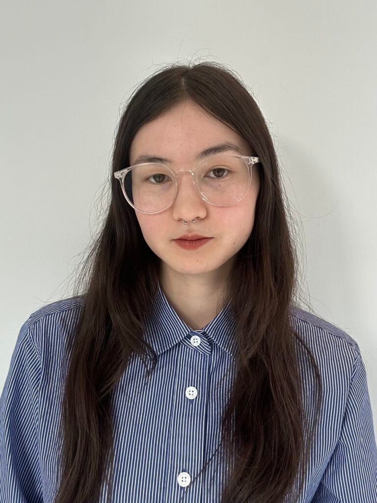Designer Lana Mingasson wears a blue-striped button-up and looks into the camera for a portrait. 