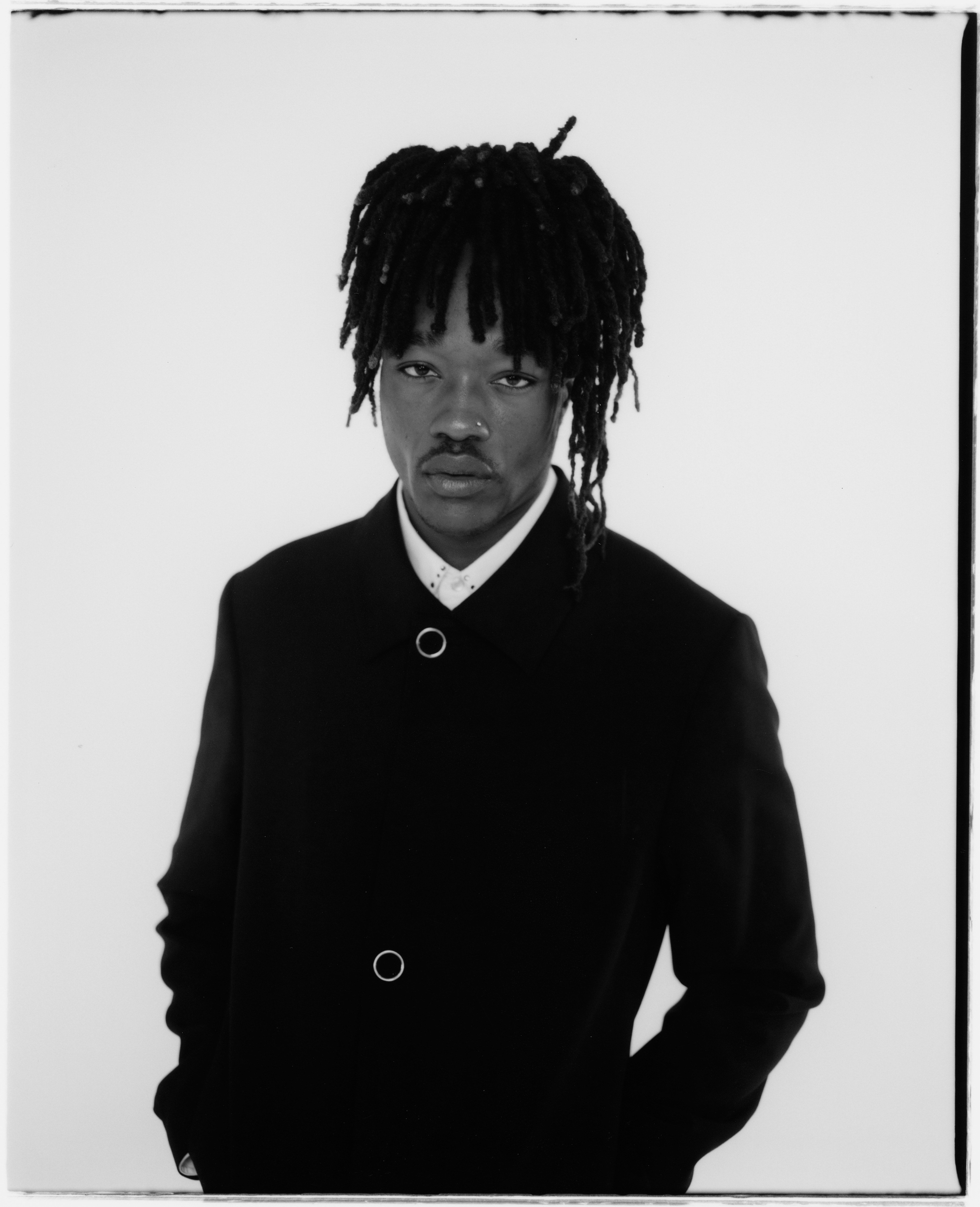 Designer Mitch Kalungi looks into the camera in a monochromatic portrait. 
