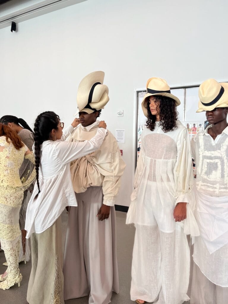 Designer Kimberly Ortega adjusting a model’s layered sculptural top prior to the runway show. 
