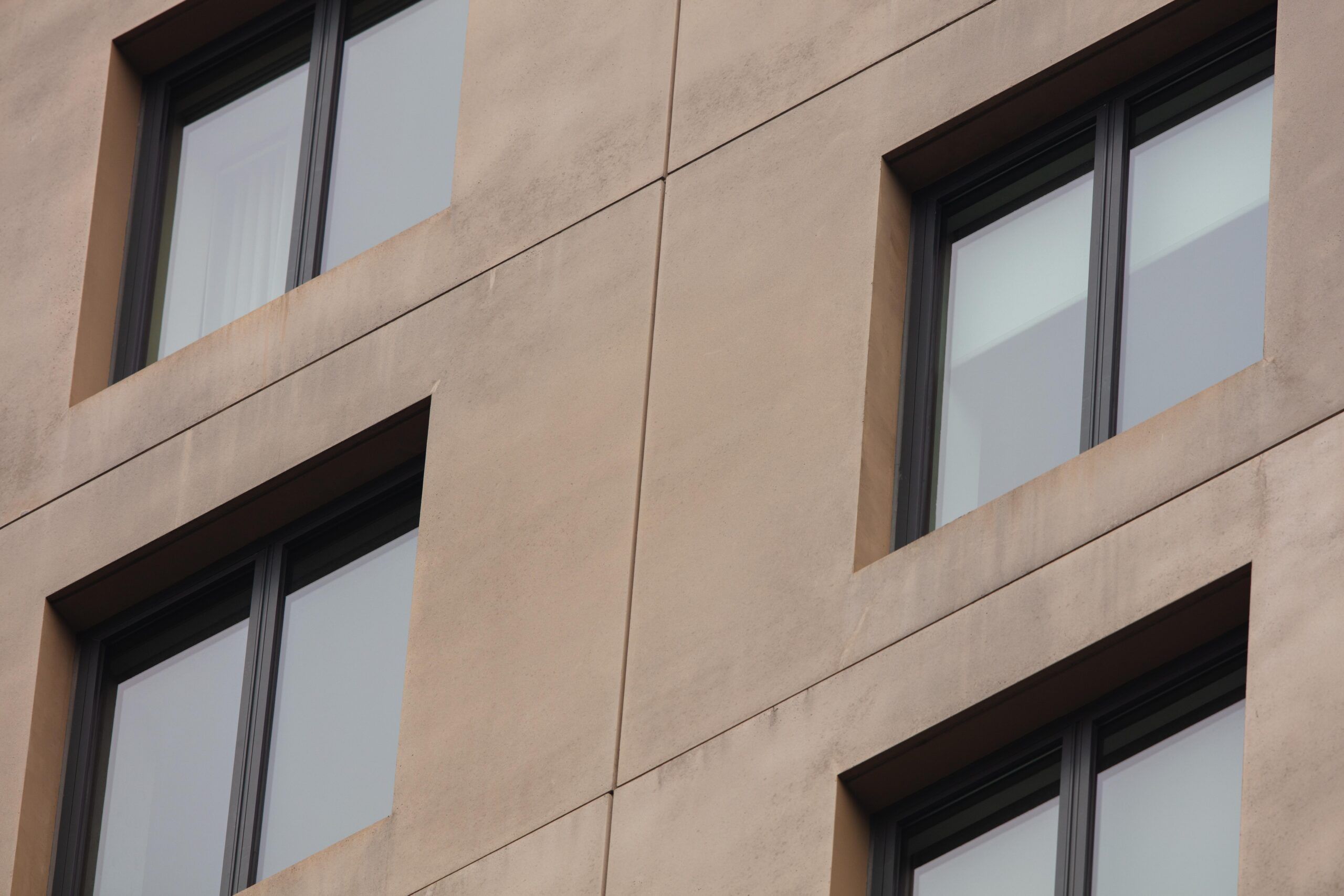 A photo of two windows on a concrete apartment building.