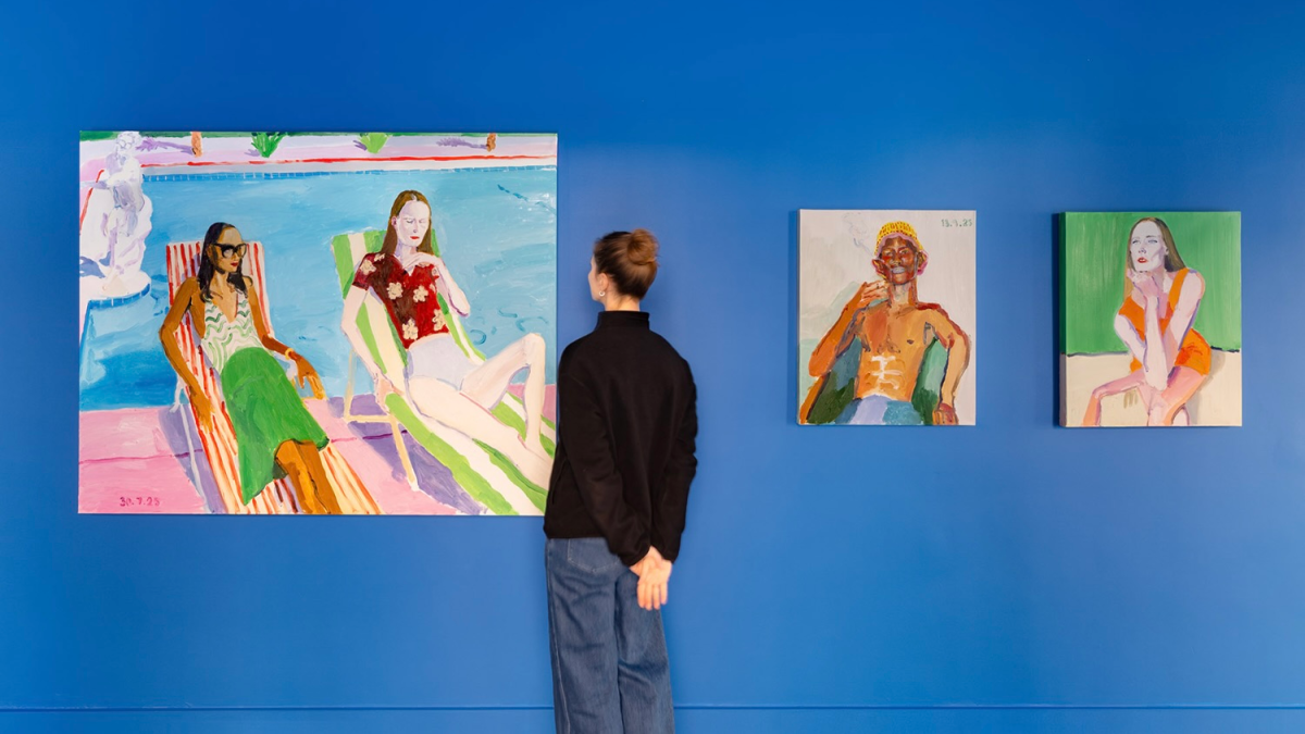 A woman stares at “Dimanche 4” alongside two other of Solà’s paintings on a blue wall at the Opera Gallery.