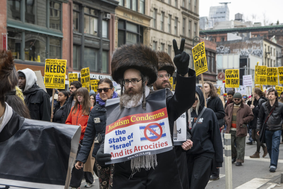 A protester holds a sign reading “Judaism Condemns the State of ‘Israel’ and its Atrocities.” 