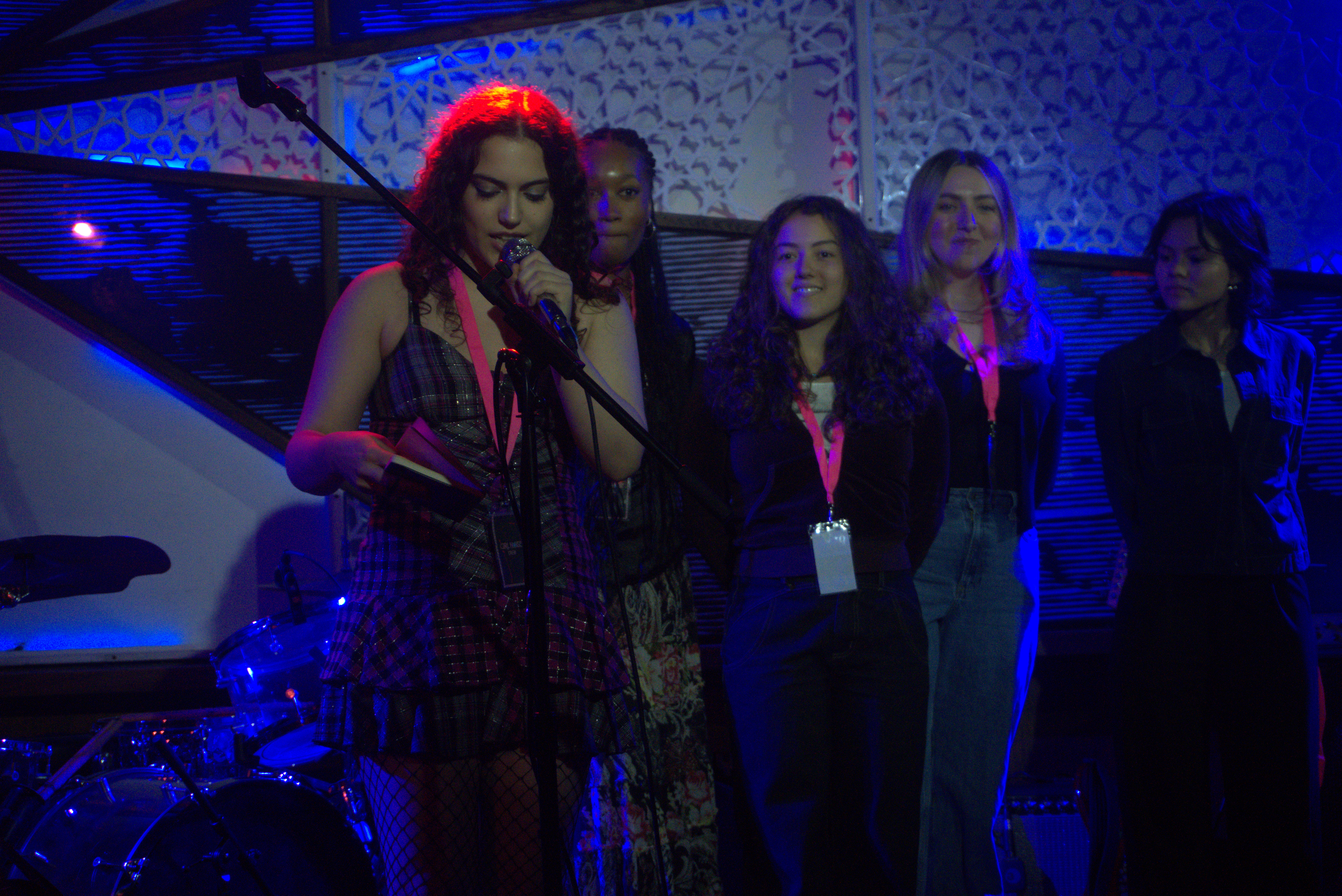On stage, Lipkin reads from her journal while organizers stand behind her.