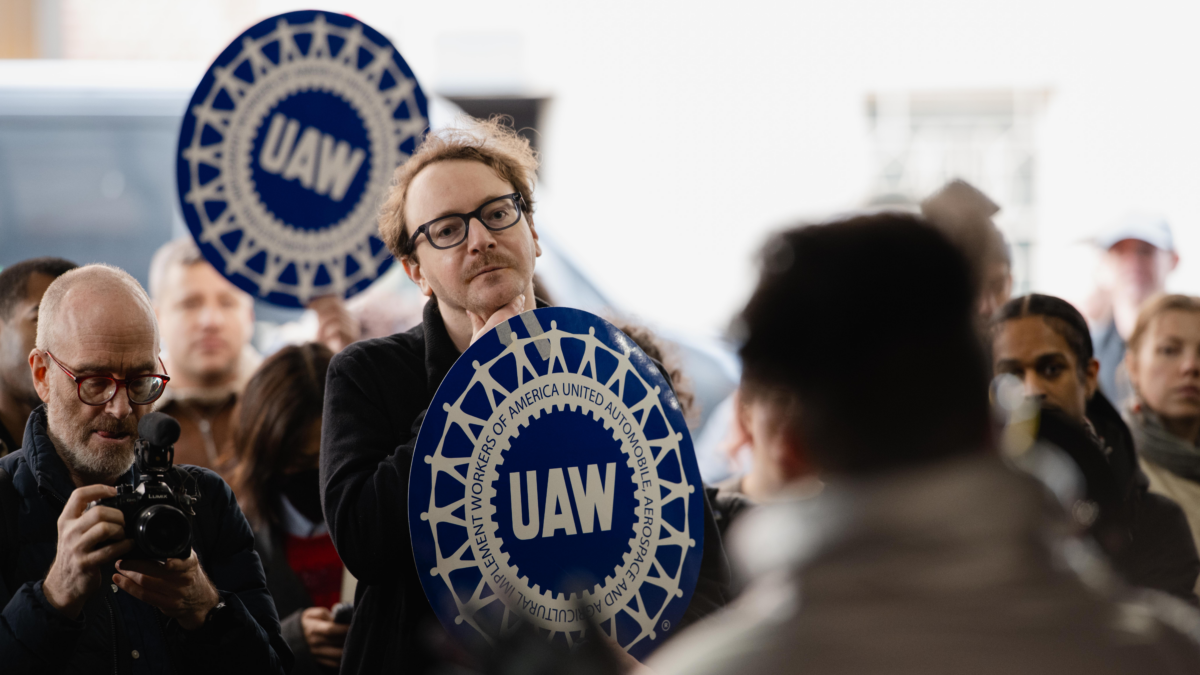 Faculty members holding blue signs that read UAW (United Auto Workers).