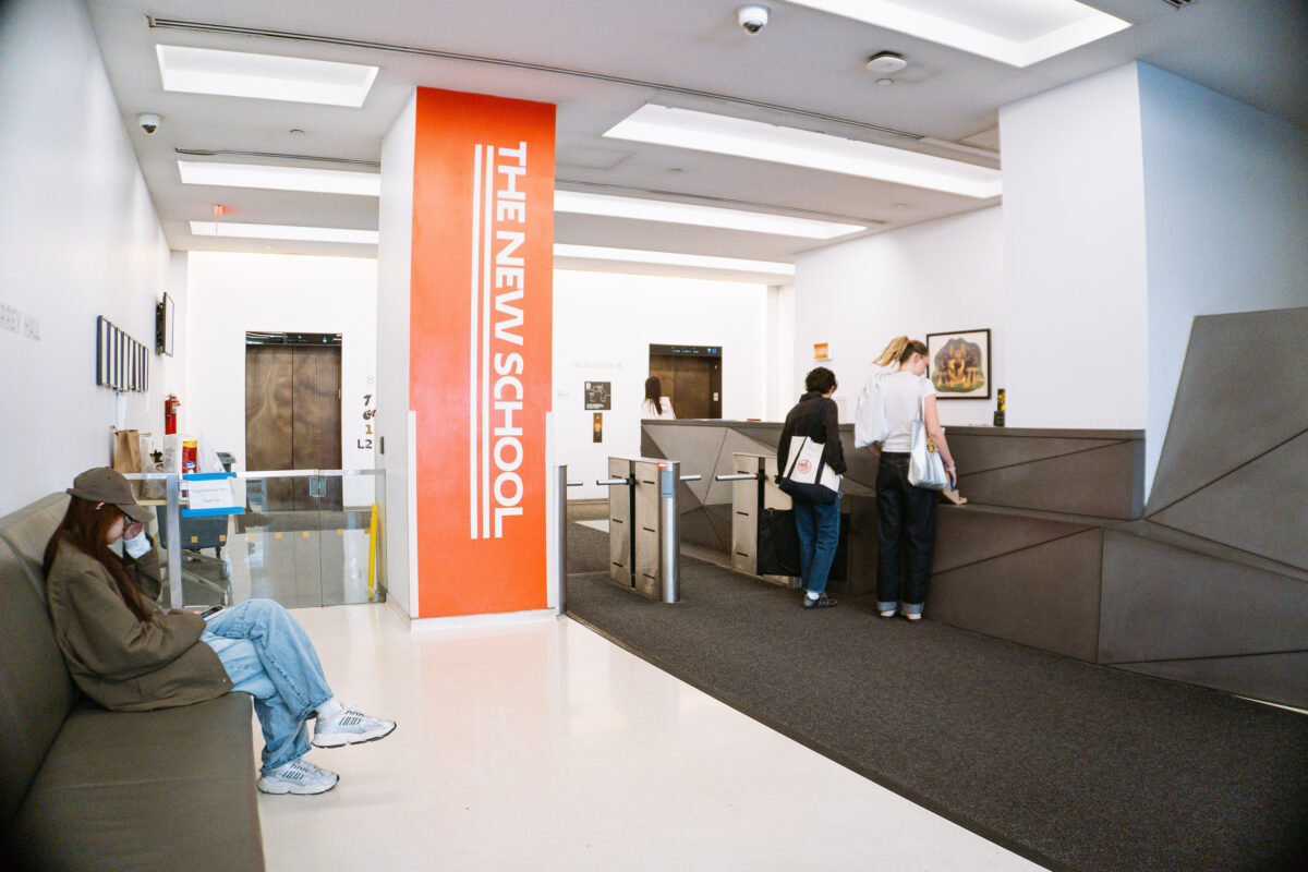 A lobby area with turnstiles, elevators, a check-in desk, and seating. 
