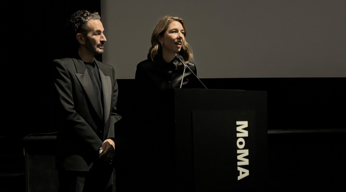 Alt text: Marc Jacobs stands next to Sofia Coppola as she addresses the audience at the Museum of Modern Art.