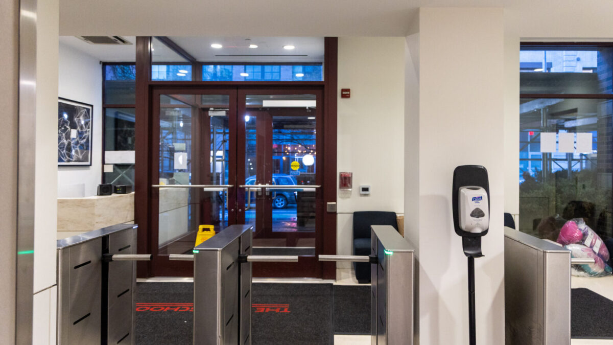 Outward-facing view of the Loeb Hall lobby with turnstiles, a security desk to the left, and a seating area to the right.