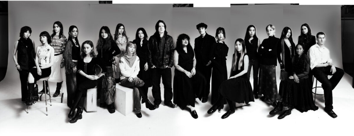 DIALECTIVE-DESIGNERS-GROUP In a wide lens monochromatic photo, 20 people pose for the camera at varying levels.